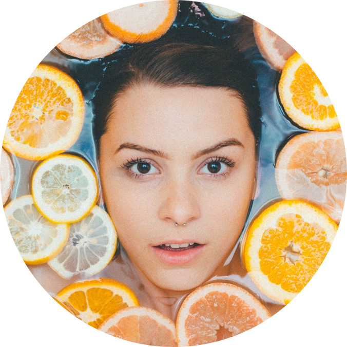 headshot of woman in water with citrus fruit slices floating around her face